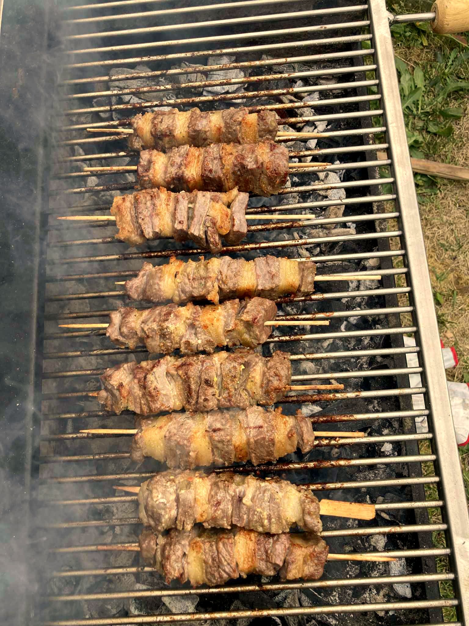 Grillrost voll mit Fleisch über glühender Kohle